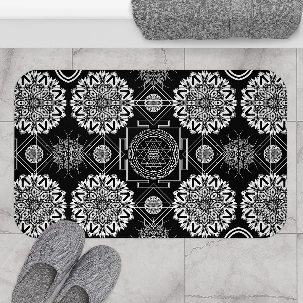 Mystical bath mat with a central Sri Yantra sacred geometry diagram surrounded by intricate white mandala snowflakes and geometric linework on deep black displayed on marble tile flooring