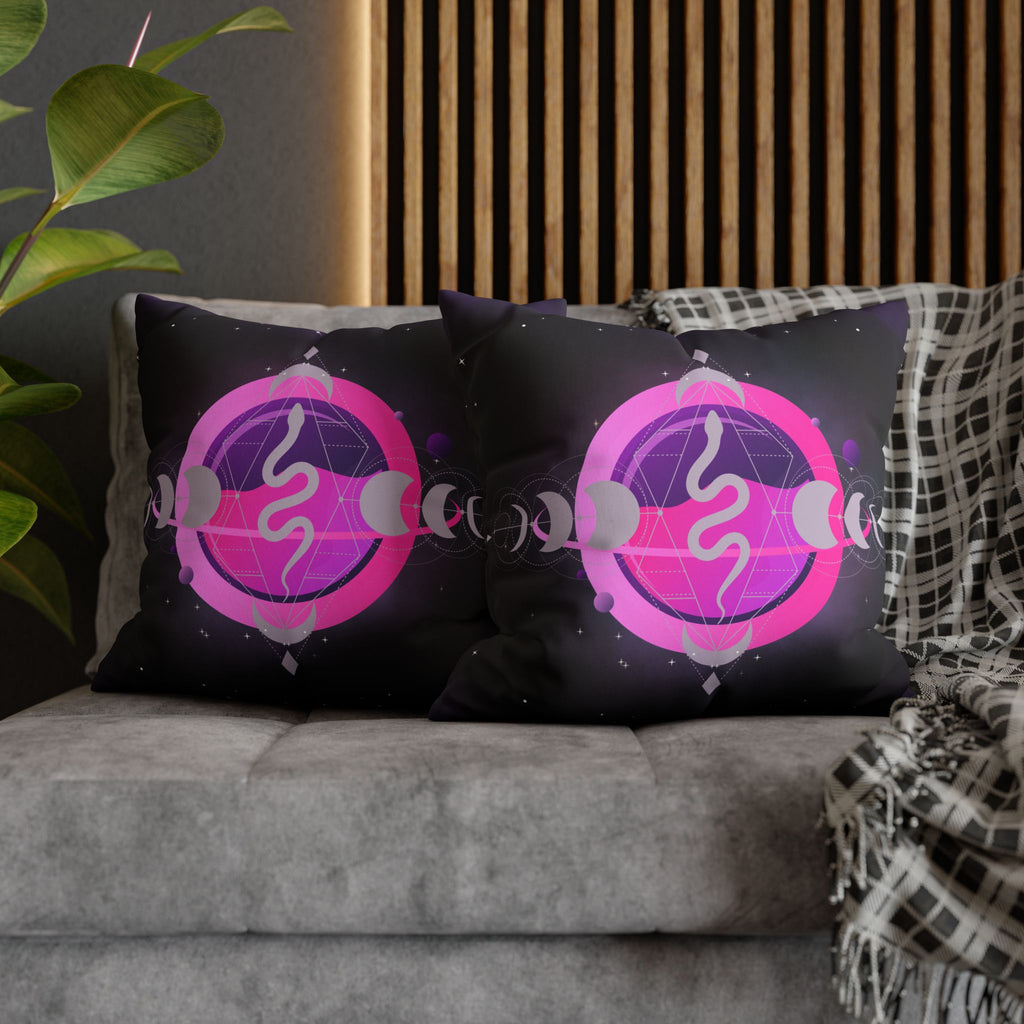 Two square throw pillows on a grey sofa featuring a silver serpent coiled inside a bold hot pink circle within a geometric diamond frame with a lavender grey moon phase sequence running horizontally and scattered stars on a deep purple-black background