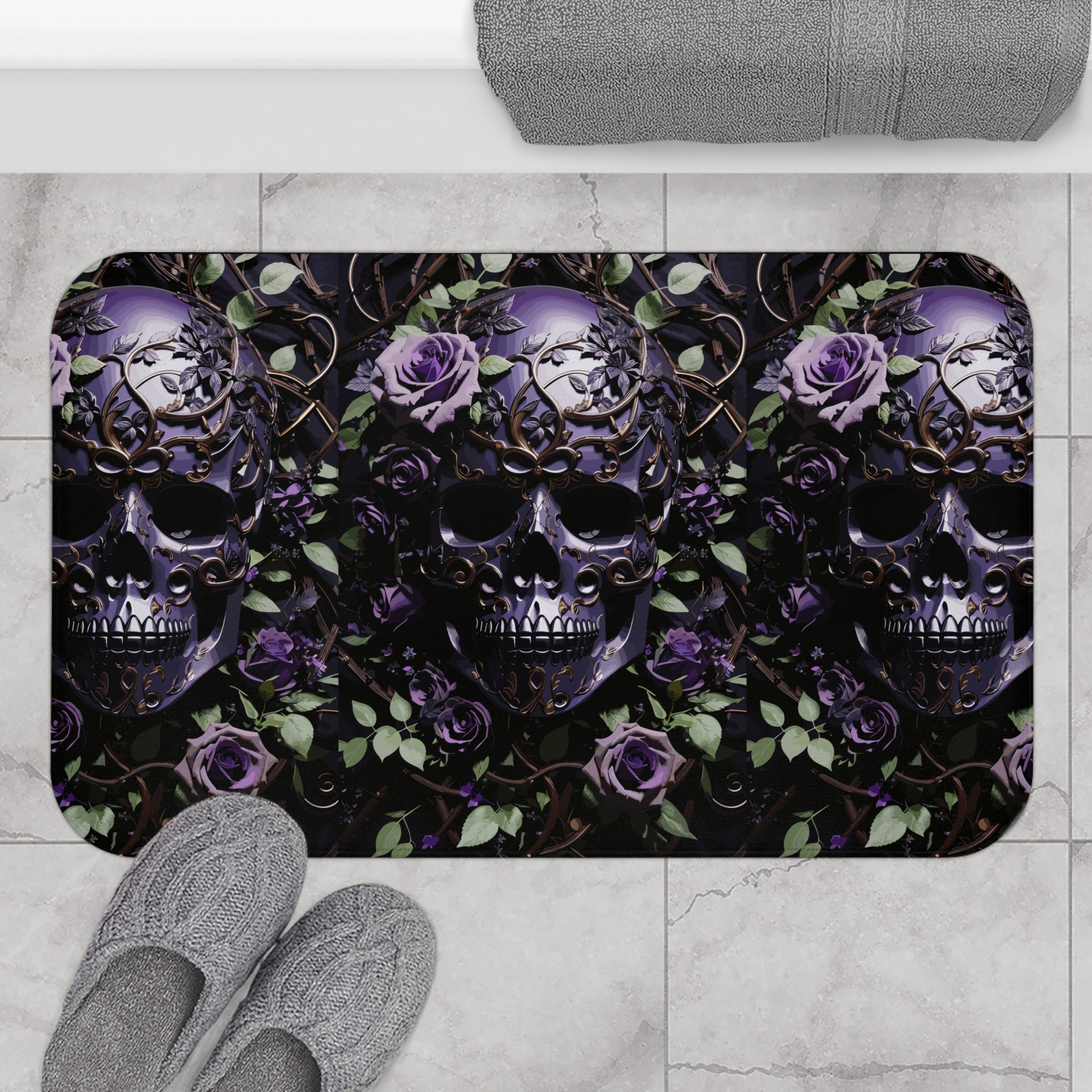Gothic bath mat with three ornate purple skulls with gold filigree surrounded by violet roses, green leaves, and bronze vine scrollwork on a deep black background displayed on marble tile flooring