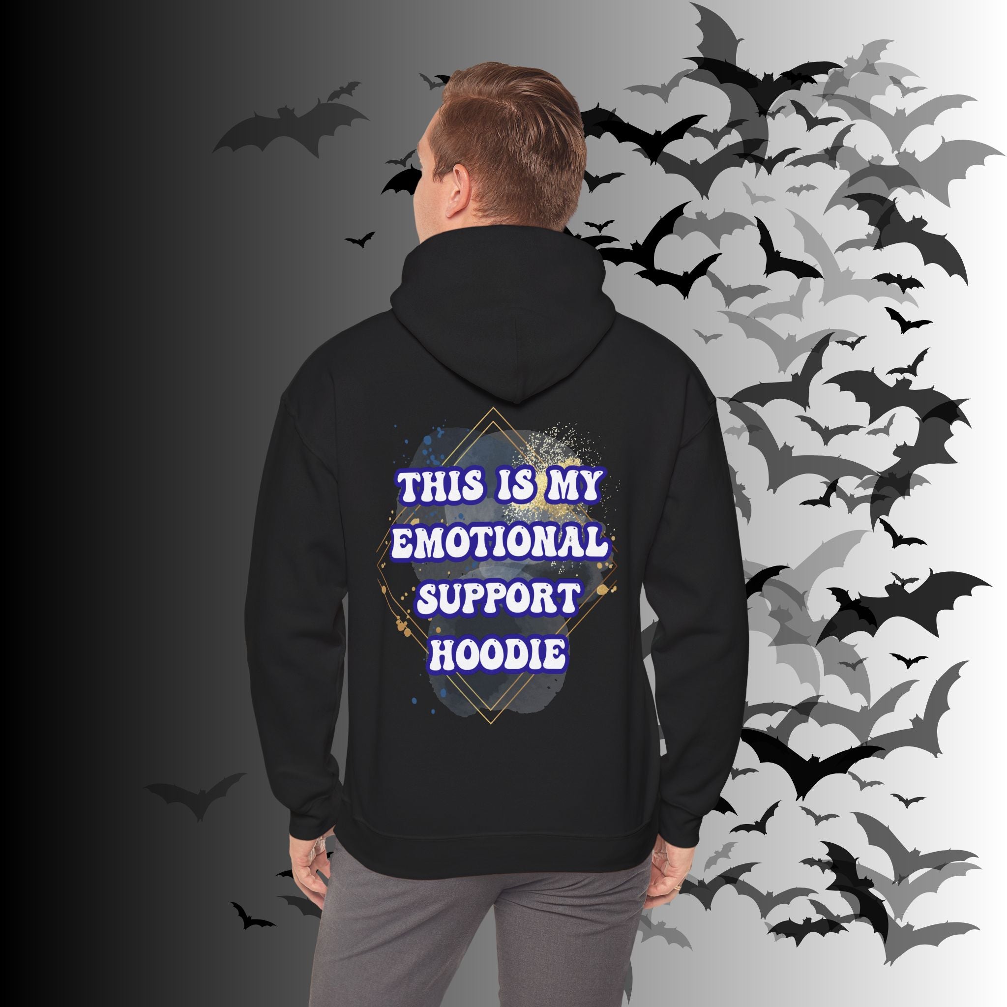 
Black pullover hoodie back print with "This Is My Emotional Support Hoodie" in bold white retro lettering inside a gold diamond frame over a blue and gold watercolor splatter background on a bat-filled background