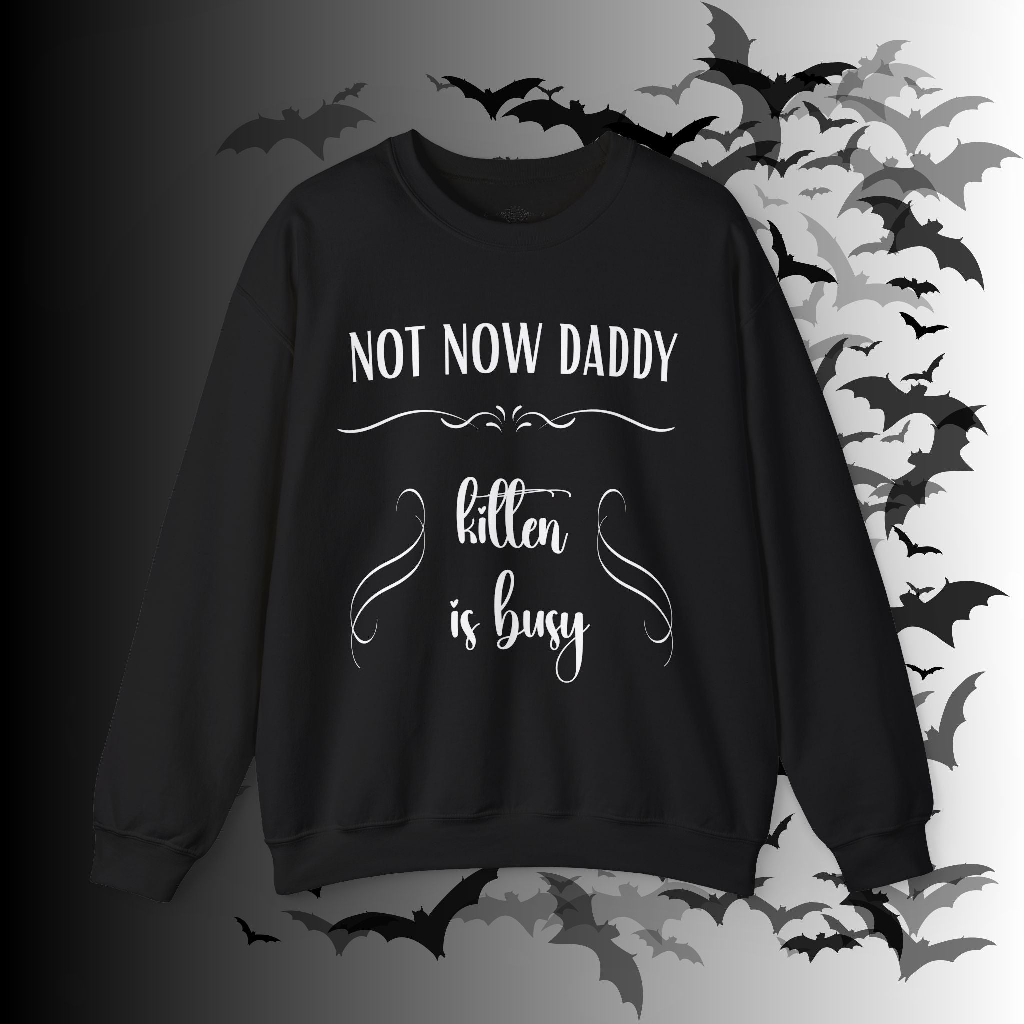 Black crewneck sweatshirt with "Not Now Daddy" in bold block lettering and "kitten is busy" in elegant script with ornamental divider on a bat-filled background