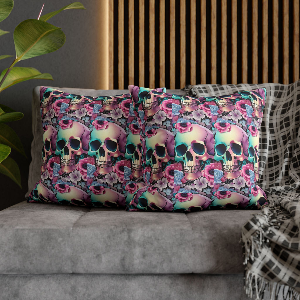 Two square throw pillows on a grey sofa featuring an all-over pattern of purple to teal gradient skulls densely packed with hot pink roses, dusty blue blooms, and lavender florals covering the entire surface