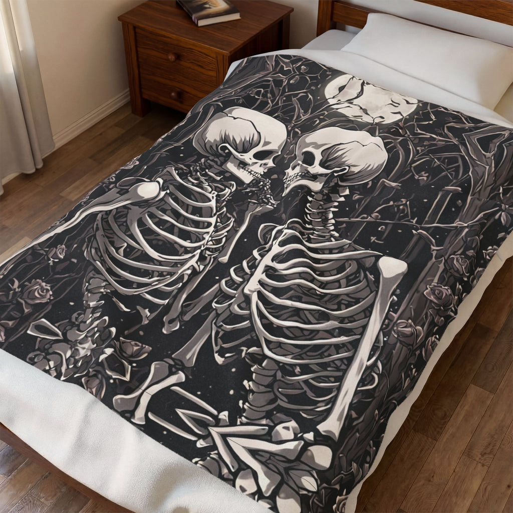 Dark charcoal throw blanket with two skeletons embracing surrounded by roses dark foliage and scattered bones 