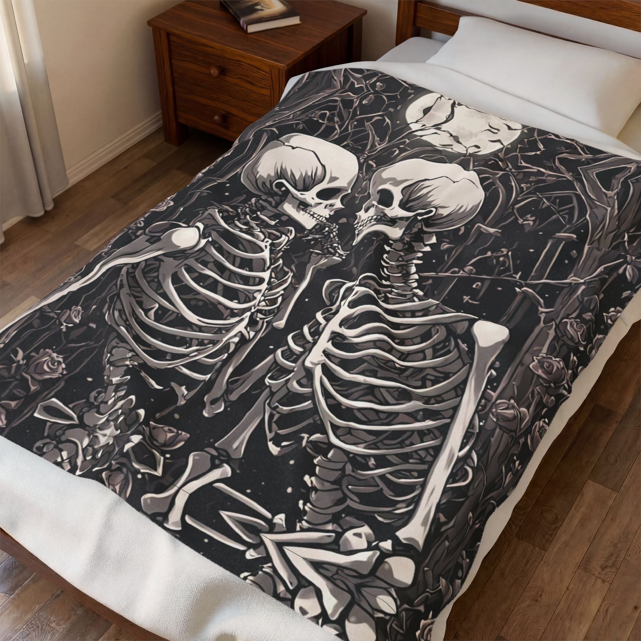 Dark charcoal throw blanket with two skeletons embracing surrounded by roses dark foliage and scattered bones 
