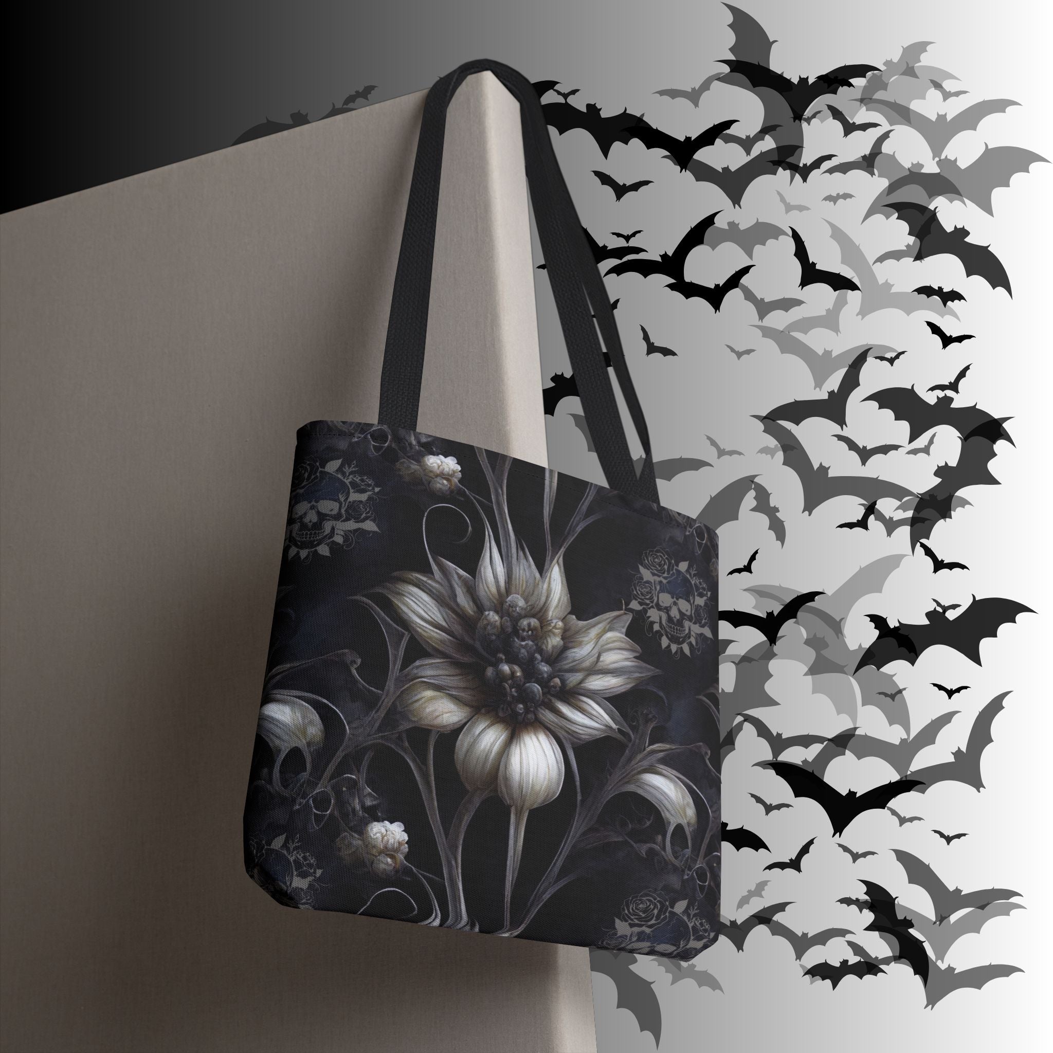 Dark charcoal polyester tote bag with large pale botanical bloom, skull motifs, rose details, and curling vine tendrils on a deep navy and grey background