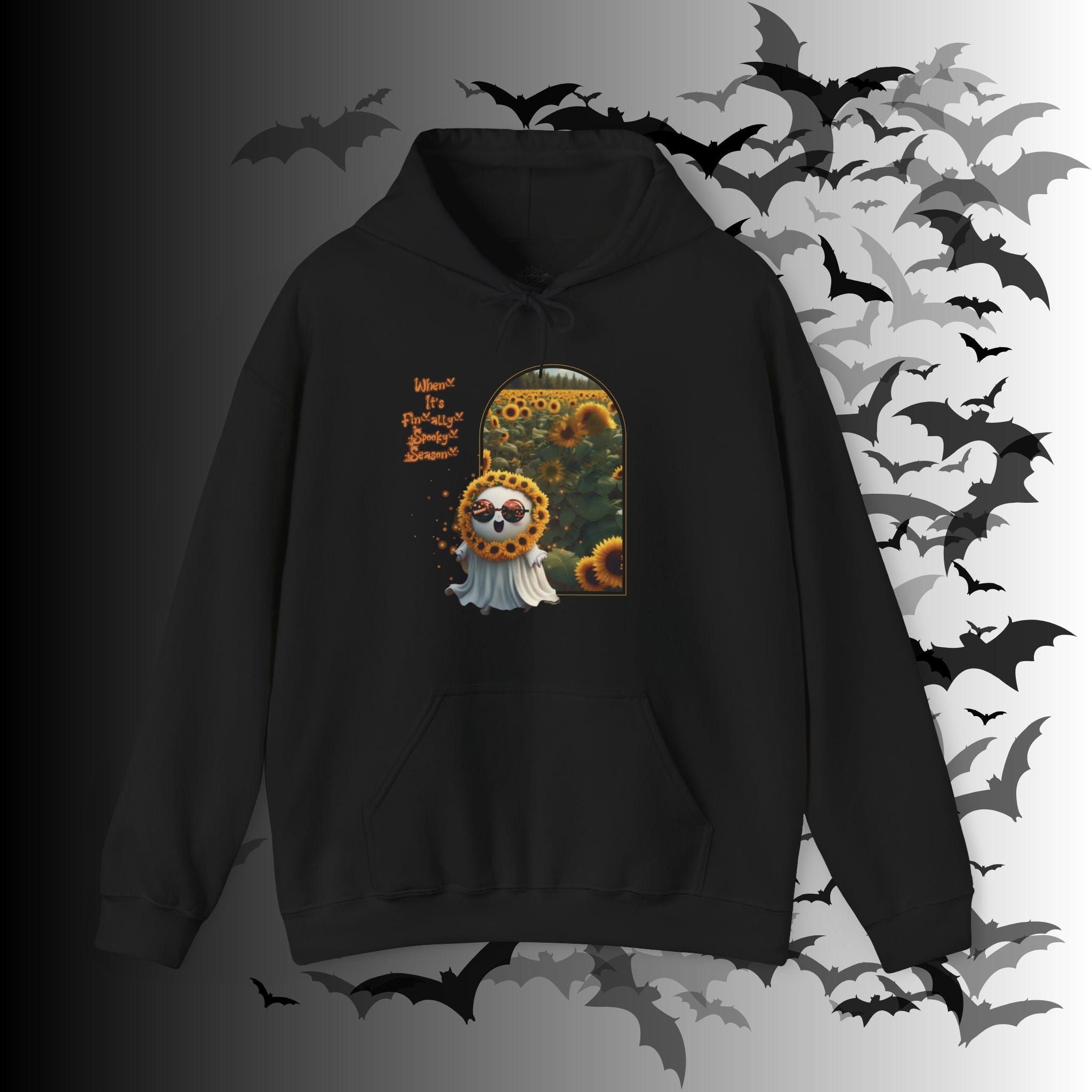 
Black pullover hoodie with kawaii ghost wearing jack-o-lantern sunglasses and sunflower crown stepping through a golden arch into a sunflower field with "When It's Finally Spooky Season" text in orange gothic lettering