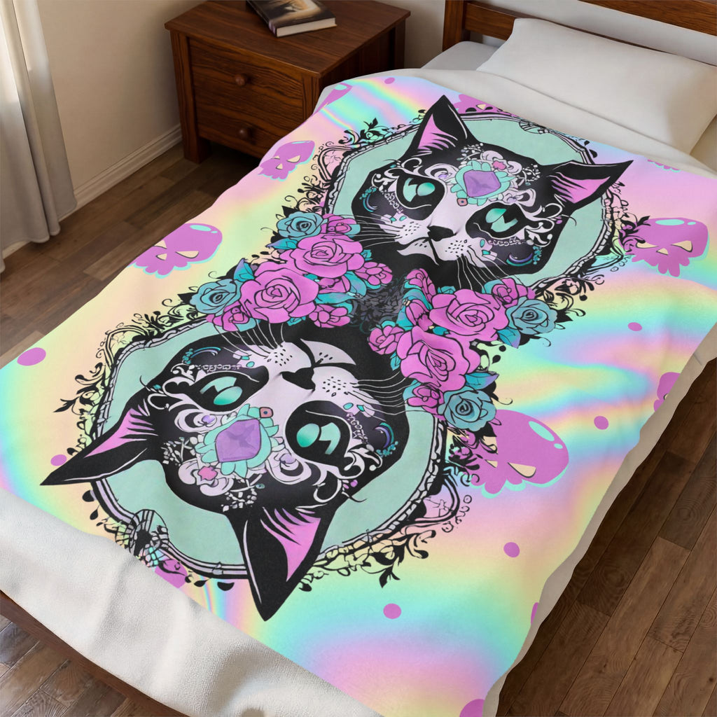 Throw blanket with two large sugar skull cats in black linework with teal gem eyes and intricate filigree, surrounded by hot pink and teal roses against a holographic pastel rainbow background shifting from mint to pink to gold