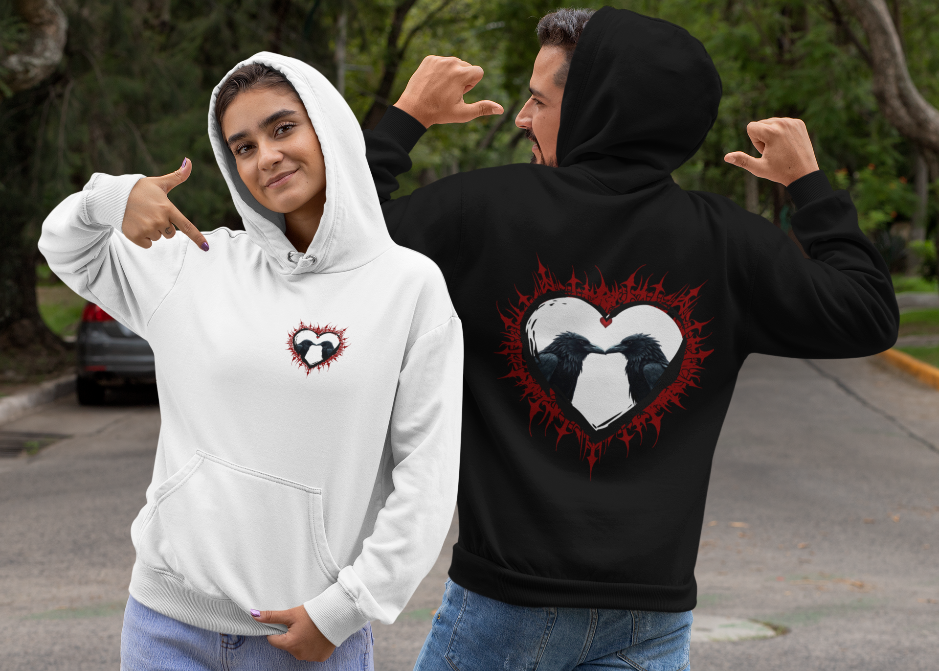 Gothic Valentine's pullover hoodie shown in white with small raven heart chest print and black with large back print of two ravens inside a jagged crimson spiked heart with full moon, worn by a couple outdoors