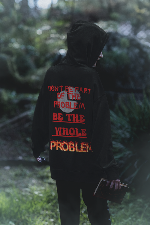 
Black pullover hoodie back print with "Don't Be Part of the Problem — Be the WHOLE Problem" in red gothic lettering with flaming text and full moon worn by a woman in a forest