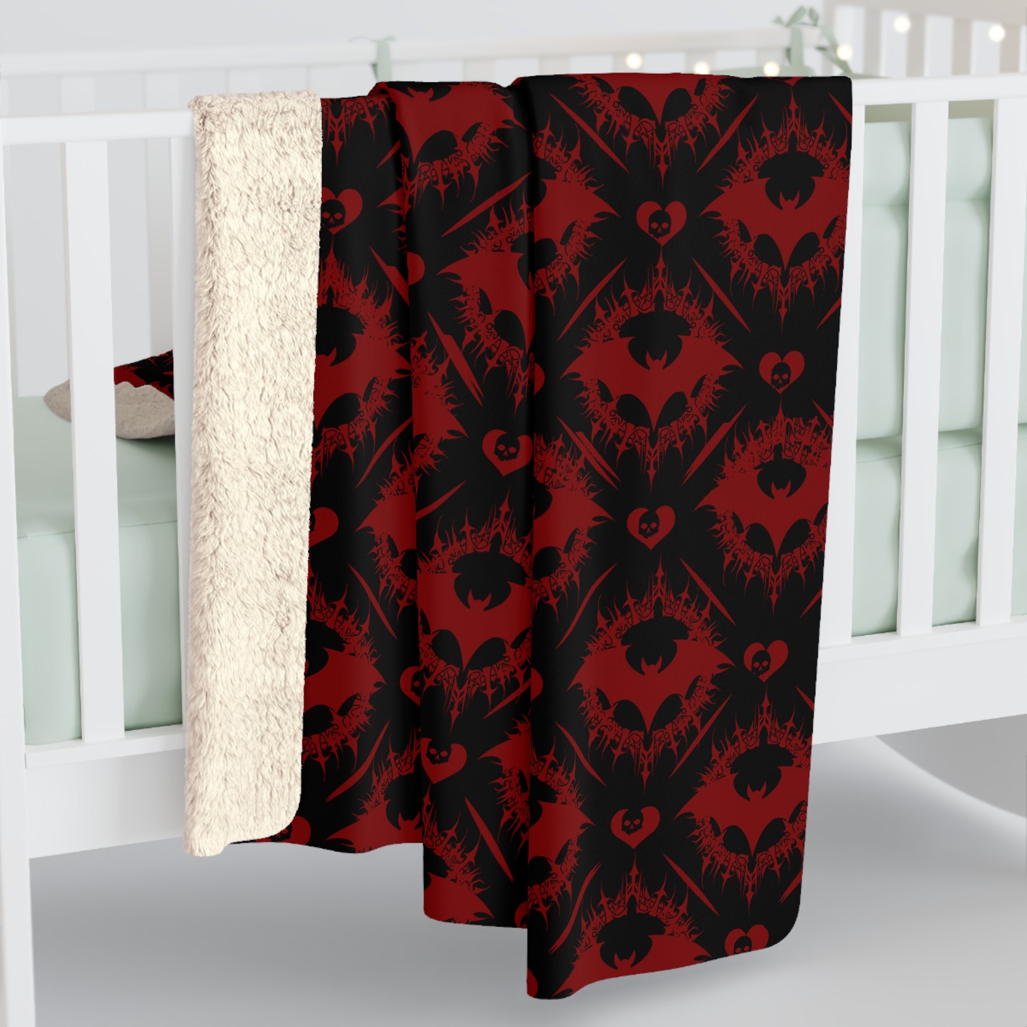 
Deep crimson and black throw blanket with repeating gothic damask pattern of bats and skull hearts displayed against a white crib background