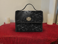 Black waterproof canvas handbag with tonal all-over bat silhouette pattern and gold turn-lock closure and hardware