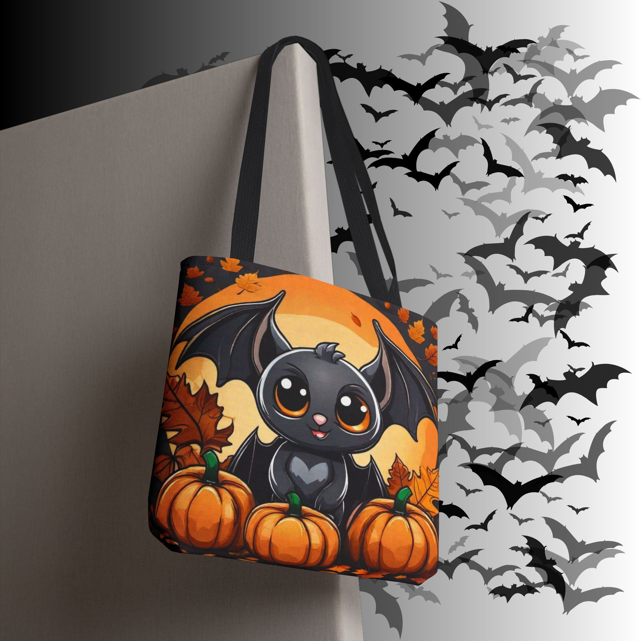 Orange and black polyester tote bag with kawaii bat with big eyes and heart chest sitting between pumpkins against a glowing full moon with autumn maple leaves