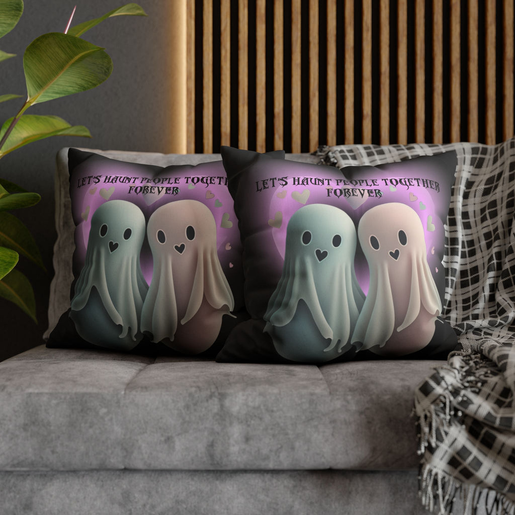 Two square throw pillows on a grey sofa featuring two soft kawaii ghosts in sage green and blush with heart-shaped eyes standing before a glowing purple heart with floating hearts and gothic script reading Let's Haunt People Together Forever