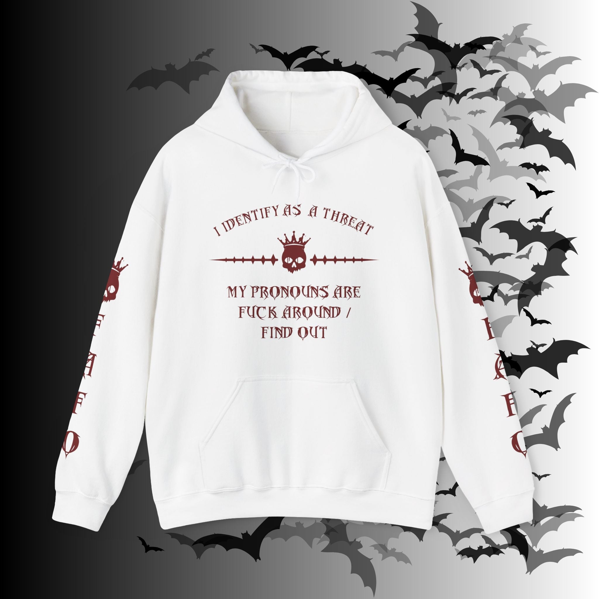 White pullover hoodie with crimson gothic crowned skull graphic and "I Identify As a Threat — My Pronouns Are Fuck Around / Find Out" text with matching skull sleeve prints on both arms on a bat-filled background