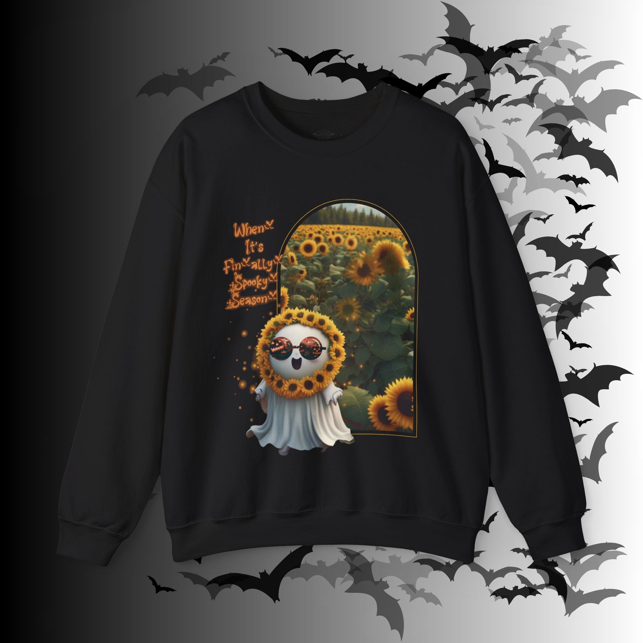 Black crewneck sweatshirt with kawaii ghost wearing jack-o-lantern sunglasses and sunflower crown stepping through a golden arch into a sunflower field with "When It's Finally Spooky Season" text in orange gothic lettering