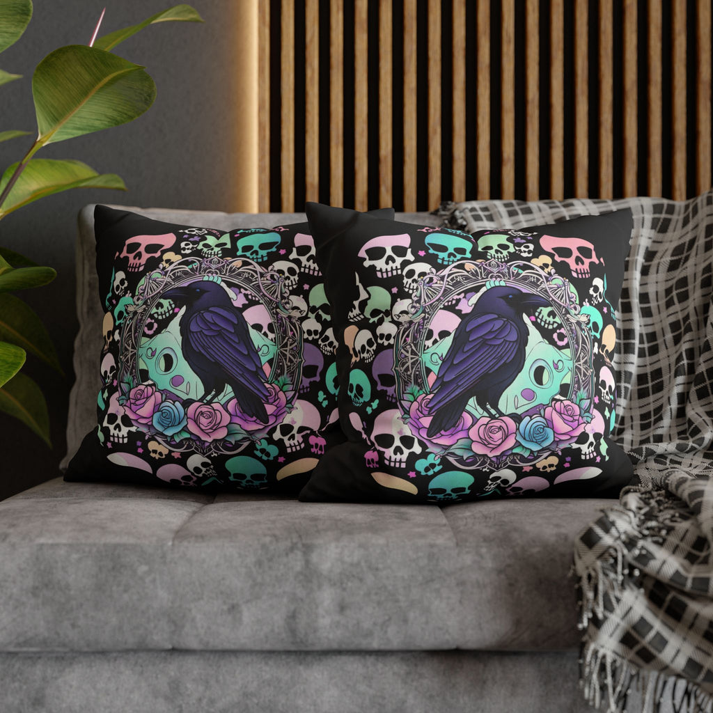 Two square throw pillows on a grey sofa featuring a deep navy raven perched inside an ornate gothic cameo frame with a kawaii skull backdrop and lavender and blue roses, surrounded by dozens of pastel skulls in mint, pink, peach, and lavender scattered across a deep black background